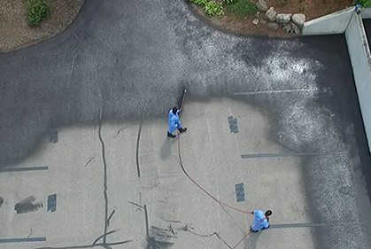 group of men applying black diamond on parking lot